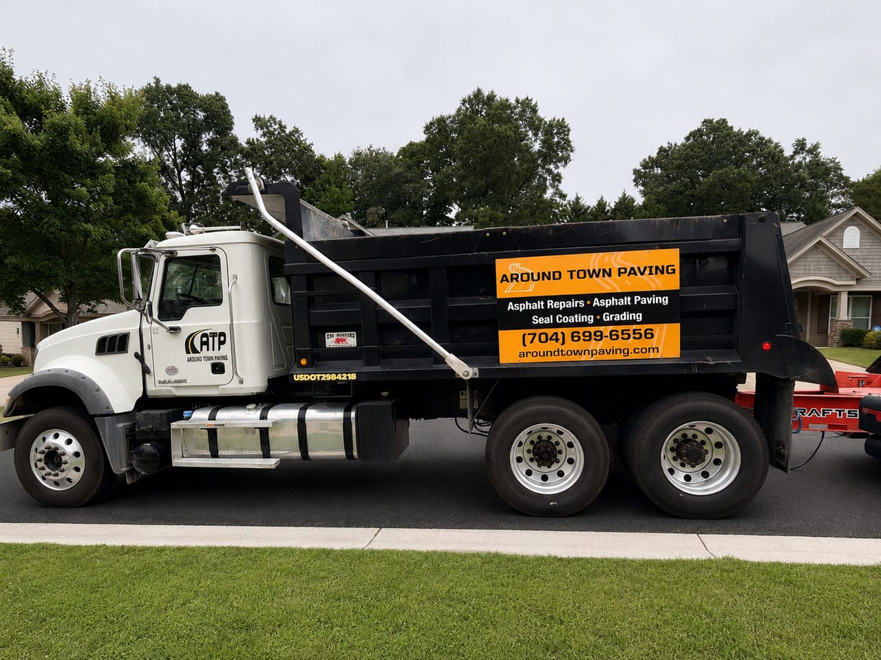 White Around Town Paving dump truck with company signage and phone number parked along a residential street in the Greater Charlotte, NC area