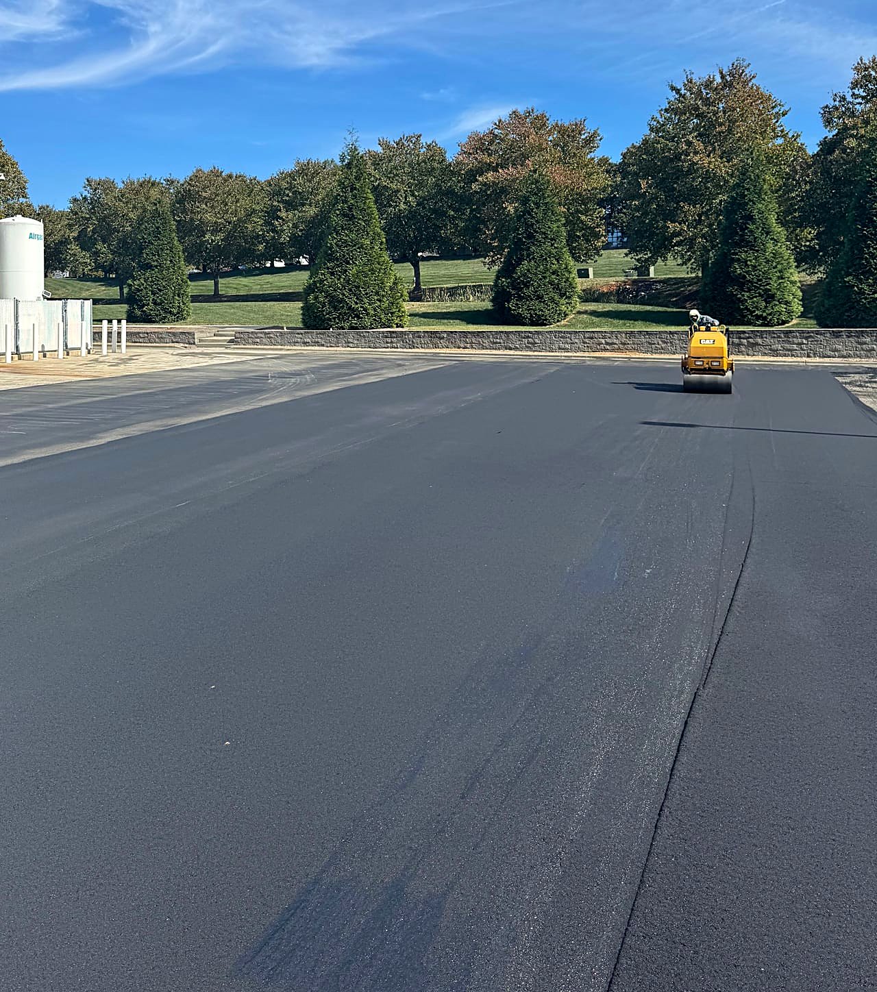 Freshly paved smooth black asphalt on a commercial lot with a roller on site, North Carolina